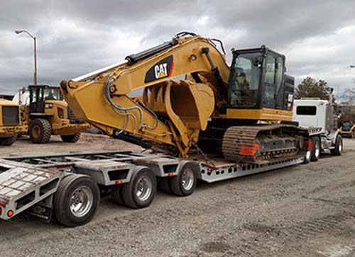 a truck carry a heavy construction vehicle on its trailer
